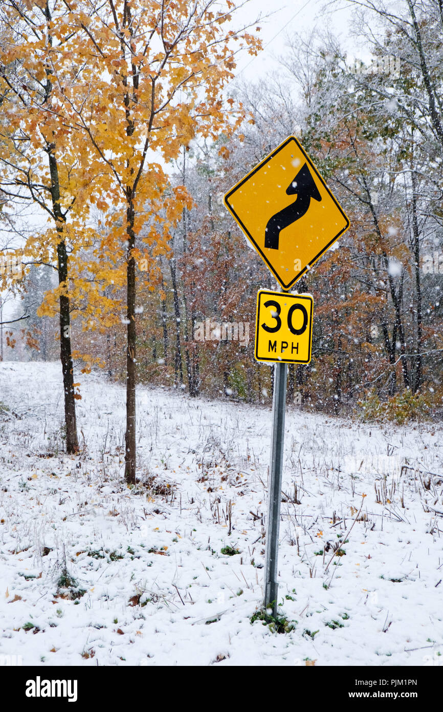 Inizio nevicata in autunno e un cartello stradale per 30 mph su una strada di campagna nelle Catskills Mountains in Upstate New York. Foto Stock