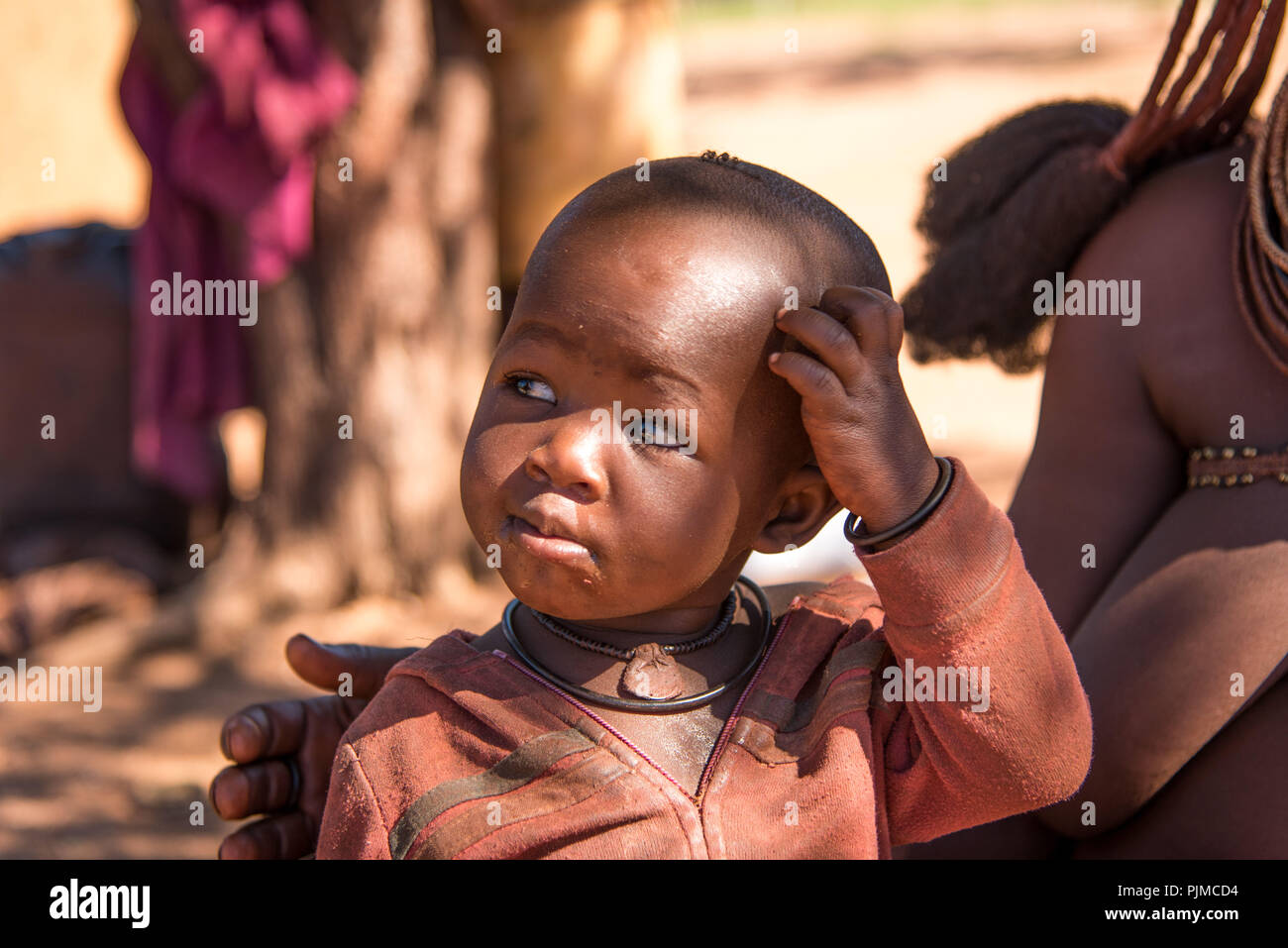 Himba Bambino sulle ginocchia della madre Foto Stock