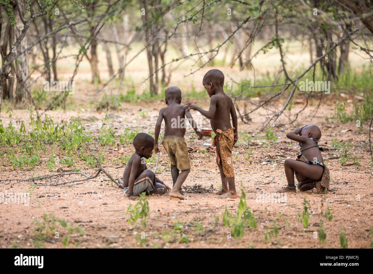 Quattro Himba bambini giocano nella foresta, a destra vicino al villaggio Foto Stock