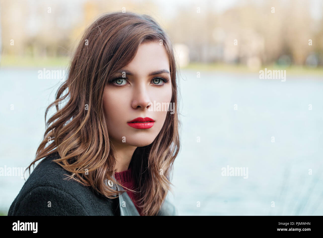 Bella ragazza con ricci sani brown acconciatura e trucco passeggiate nel parco Foto Stock