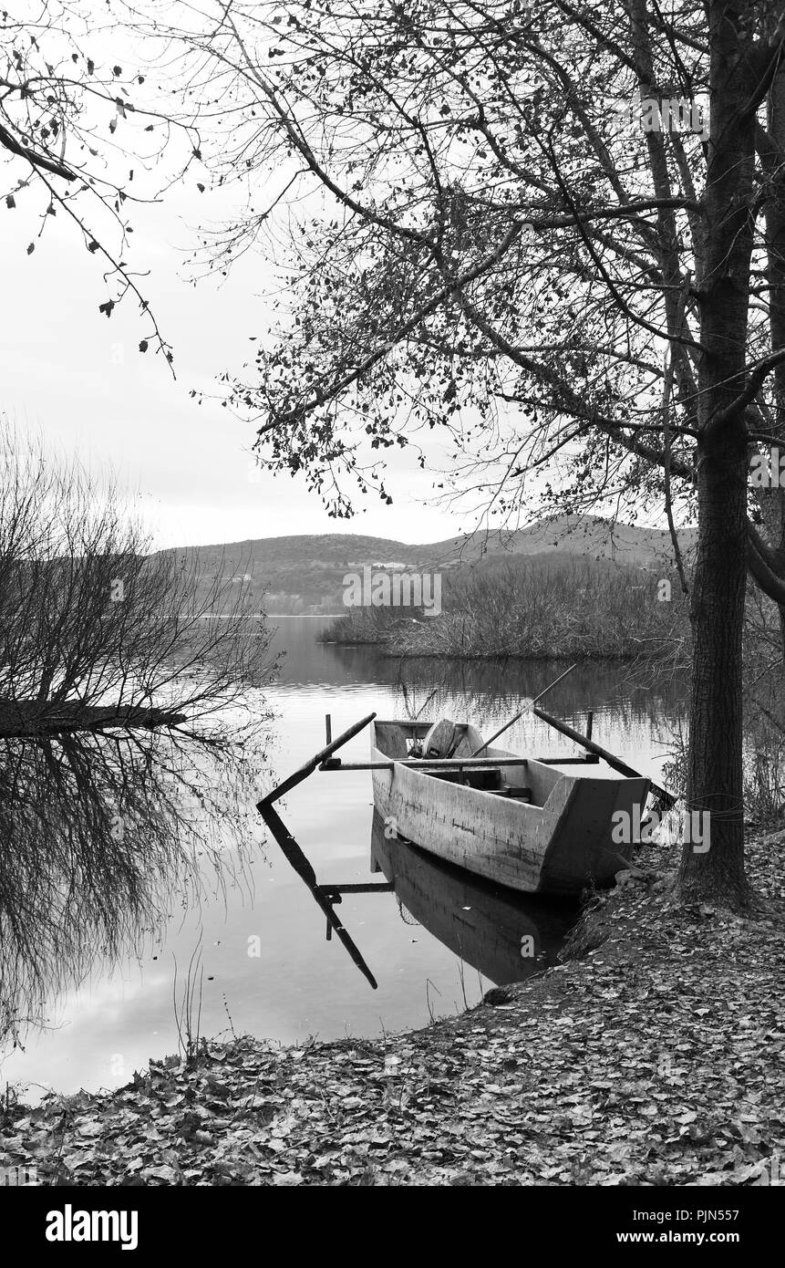 La barca di legno sulle rive del lago in bianco e nero Foto Stock