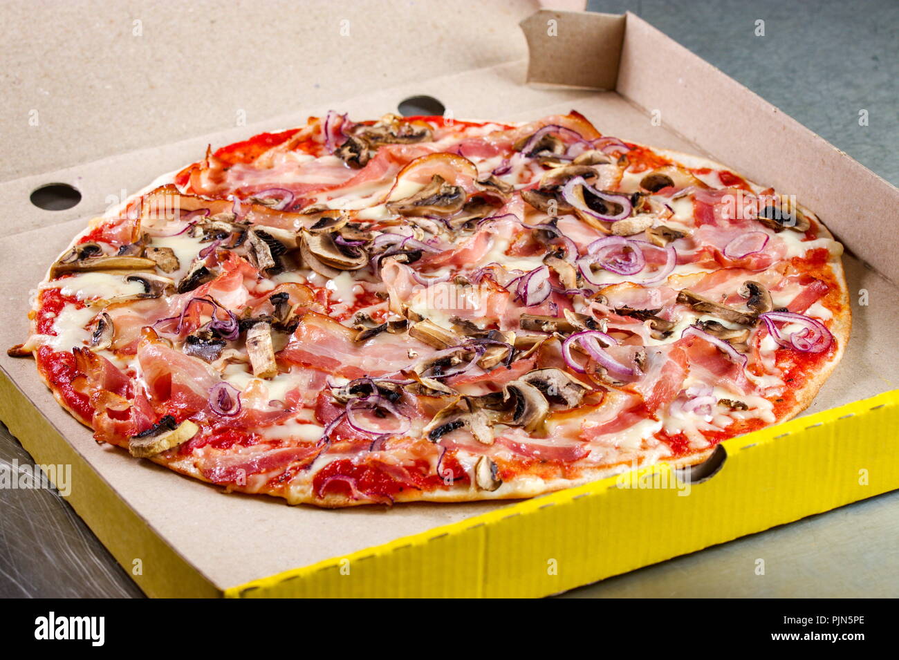 Pizza prosciutto crudo preparato e presentato in imballaggi di cartone Foto Stock