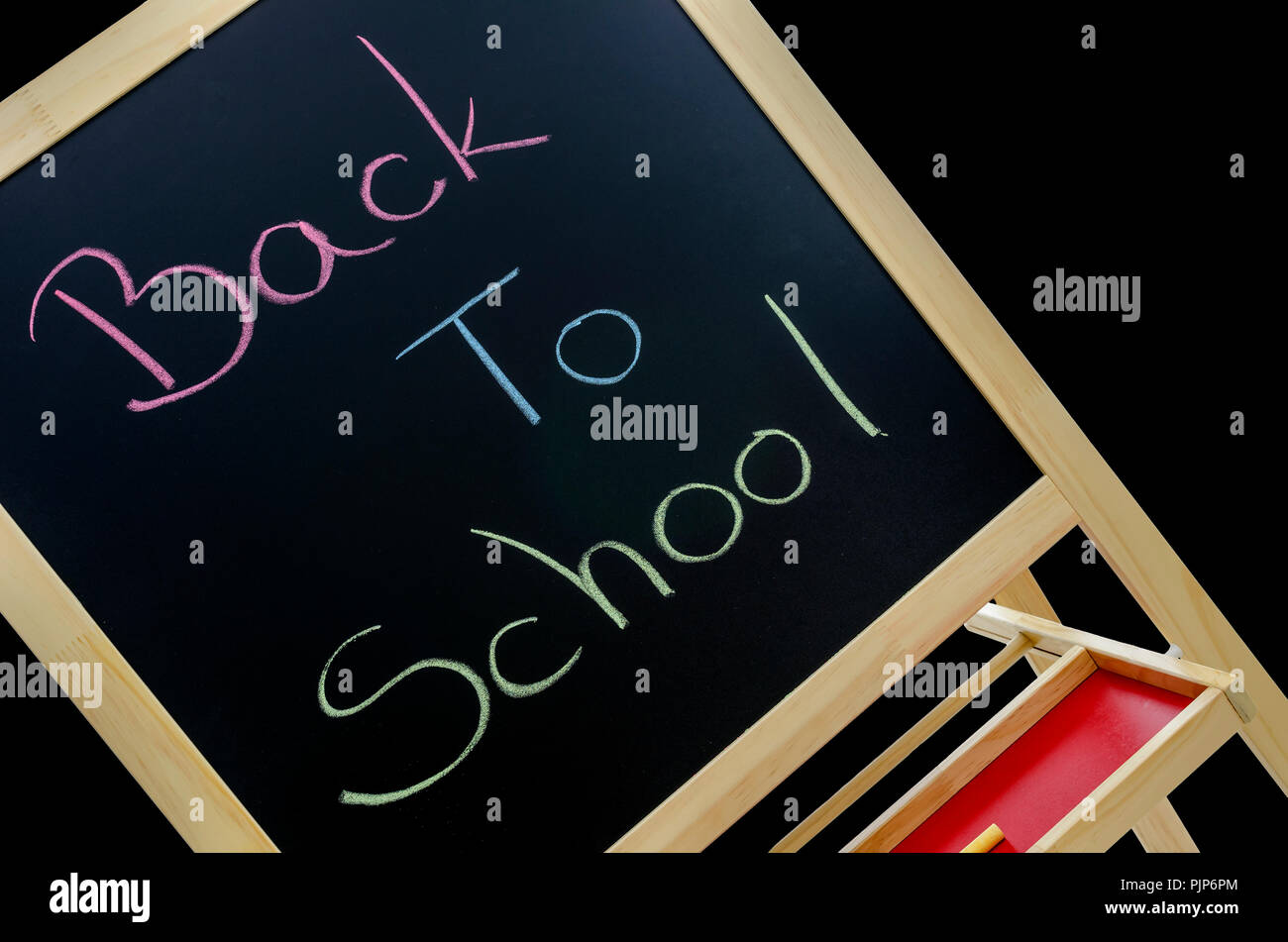 Il testo si torna a scuola scritto in vari colori sulla lavagna. Isolato su sfondo nero. Foto Stock