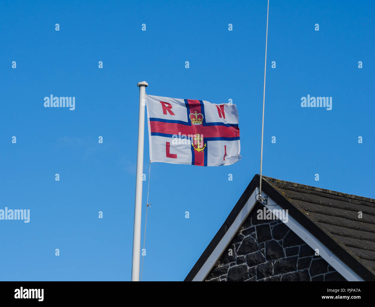 RNLI battenti bandiera nella brezza sopra Donaghadee scialuppa di salvataggio station Foto Stock