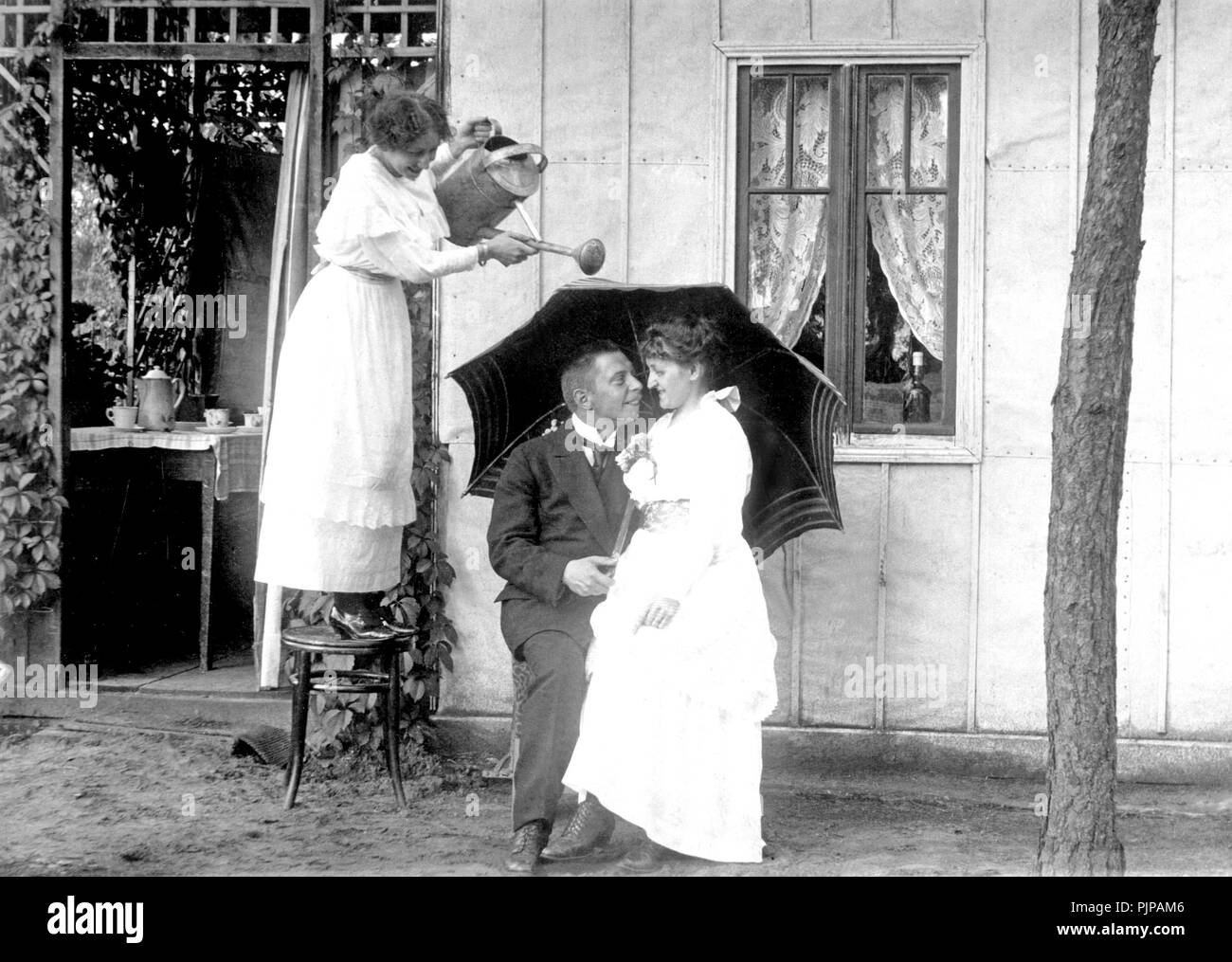 La gelosia, donna disturba amare giovane con un annaffiatoio, questo protegge con un ombrello, 1920s, Germania Foto Stock