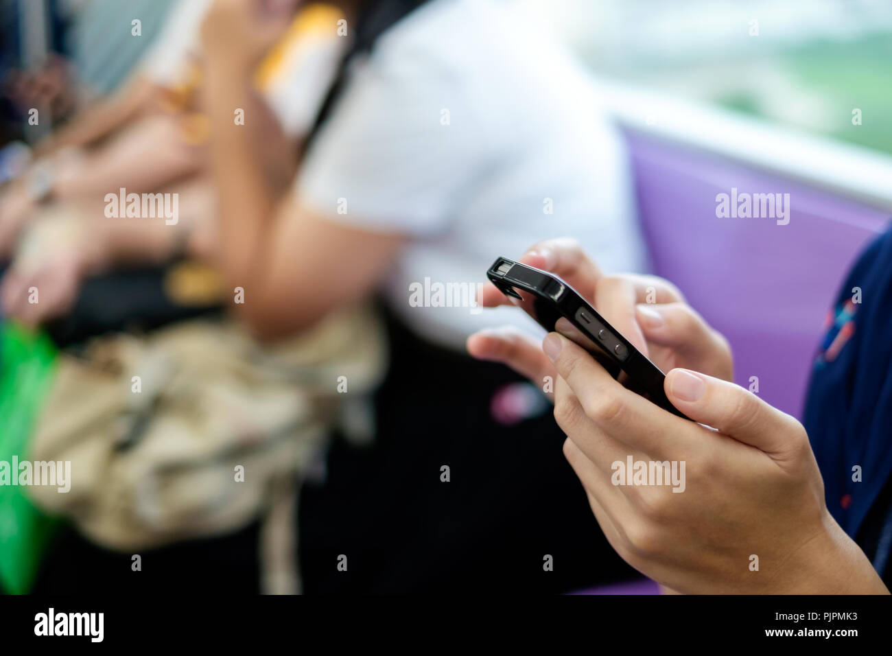 Utilizzando il telefono cellulare per navigare su internet e scrivere messaggi in transito pubblico. Foto Stock