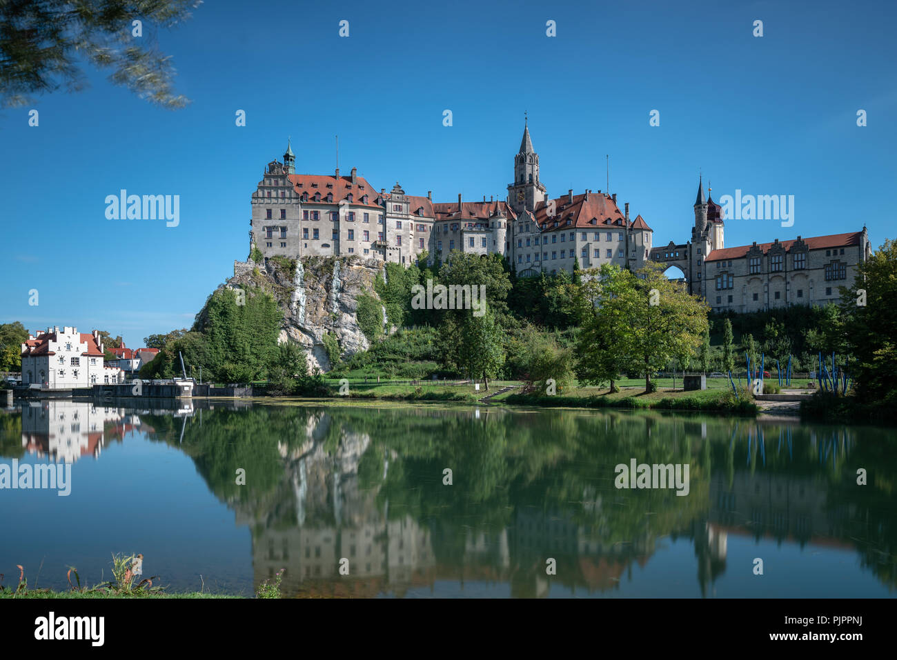 Il Hohenzollernschloss in Sigmaringen nel giorno prima di un cielo privo di nuvole con il Danubio in primo piano. ** Das Hohenzollernschloss in Sigmaringen Foto Stock