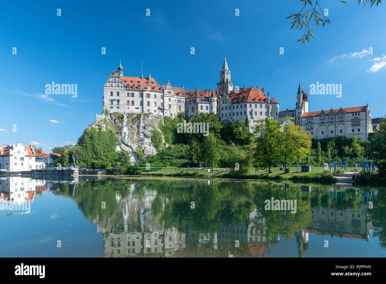 Il Hohenzollernschloss in Sigmaringen nel giorno prima di un cielo privo di nuvole con il Danubio in primo piano. ** Das Hohenzollernschloss in Sigmaringen Foto Stock