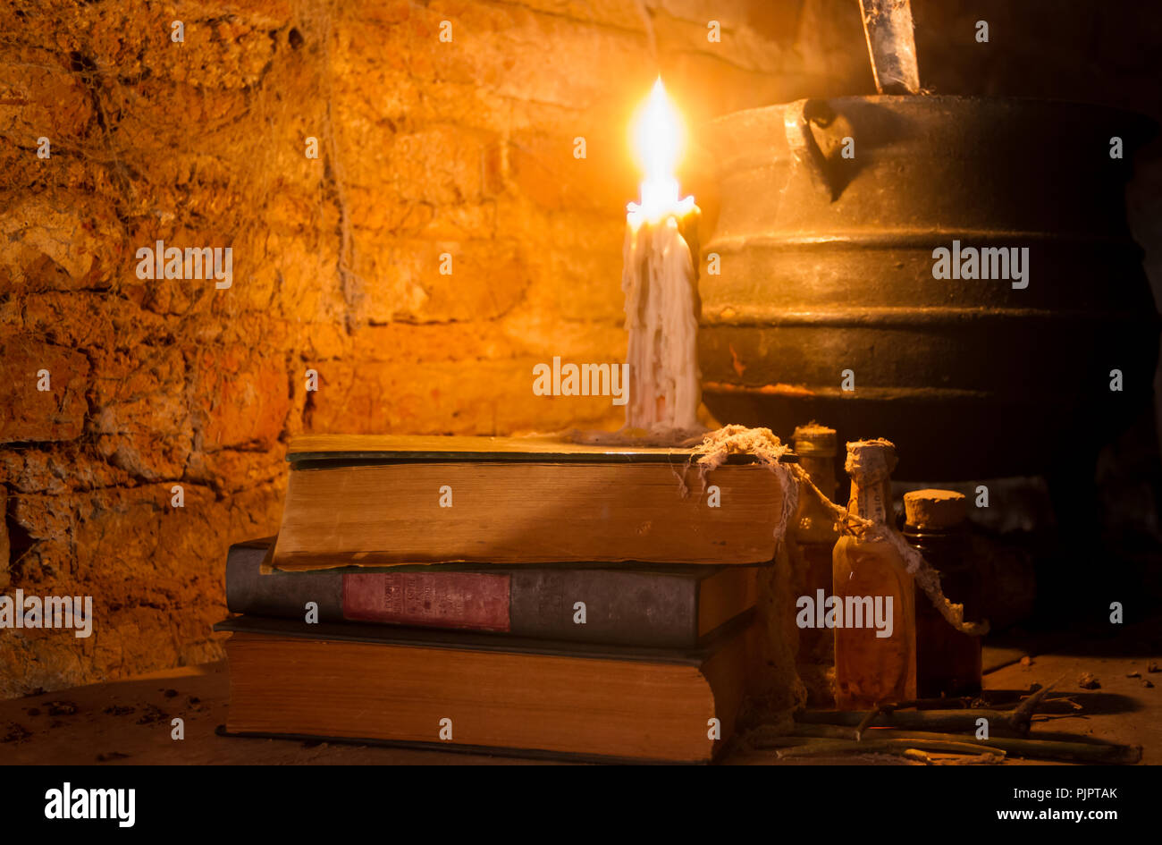 Incantesimo di strega notte con candele e pot con fuoco tra ragnatele e antica terra Foto Stock
