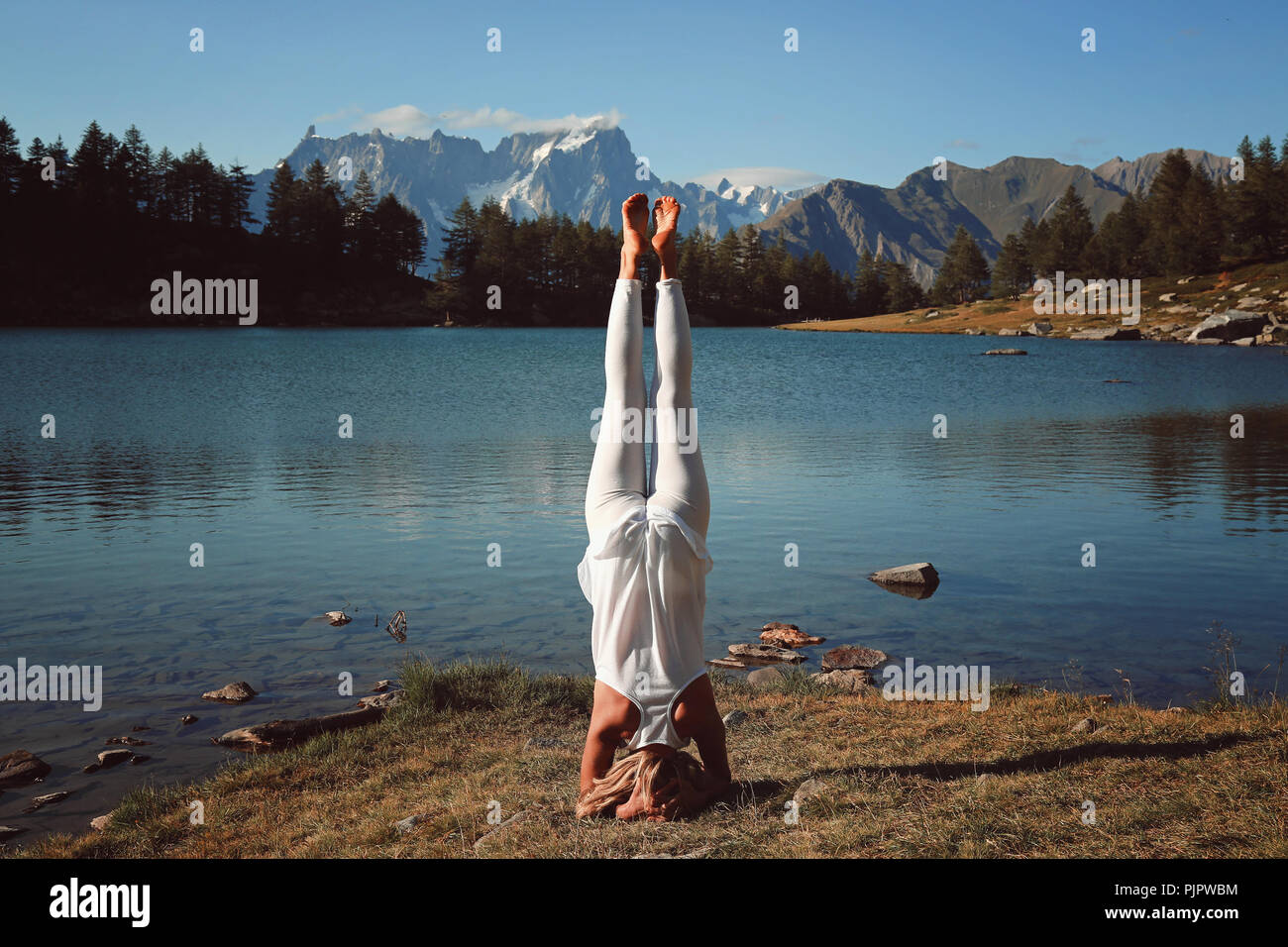 La donna a praticare yoga sul lungolago. La luce del tramonto Foto Stock