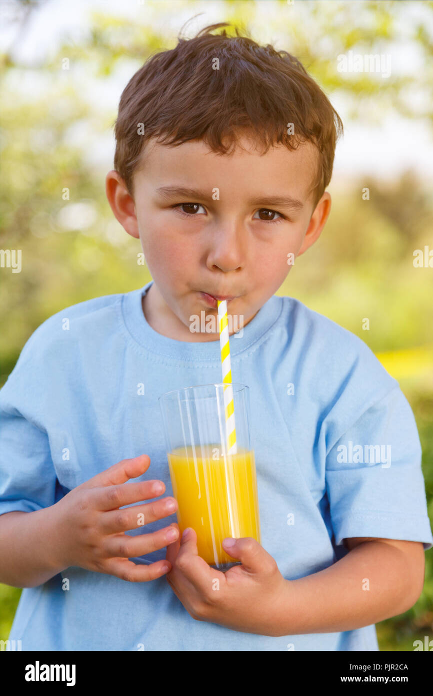 Bambino kid ragazzino di bere succo di arancia drink all'aperto formato ritratto all'aperto al di fuori del bicchiere Foto Stock