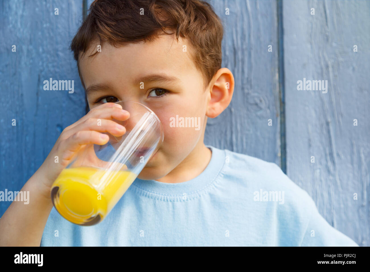 Bambino kid ragazzino di bere succo di arancia drink all'aperto all'aperto al di fuori del bicchiere Foto Stock