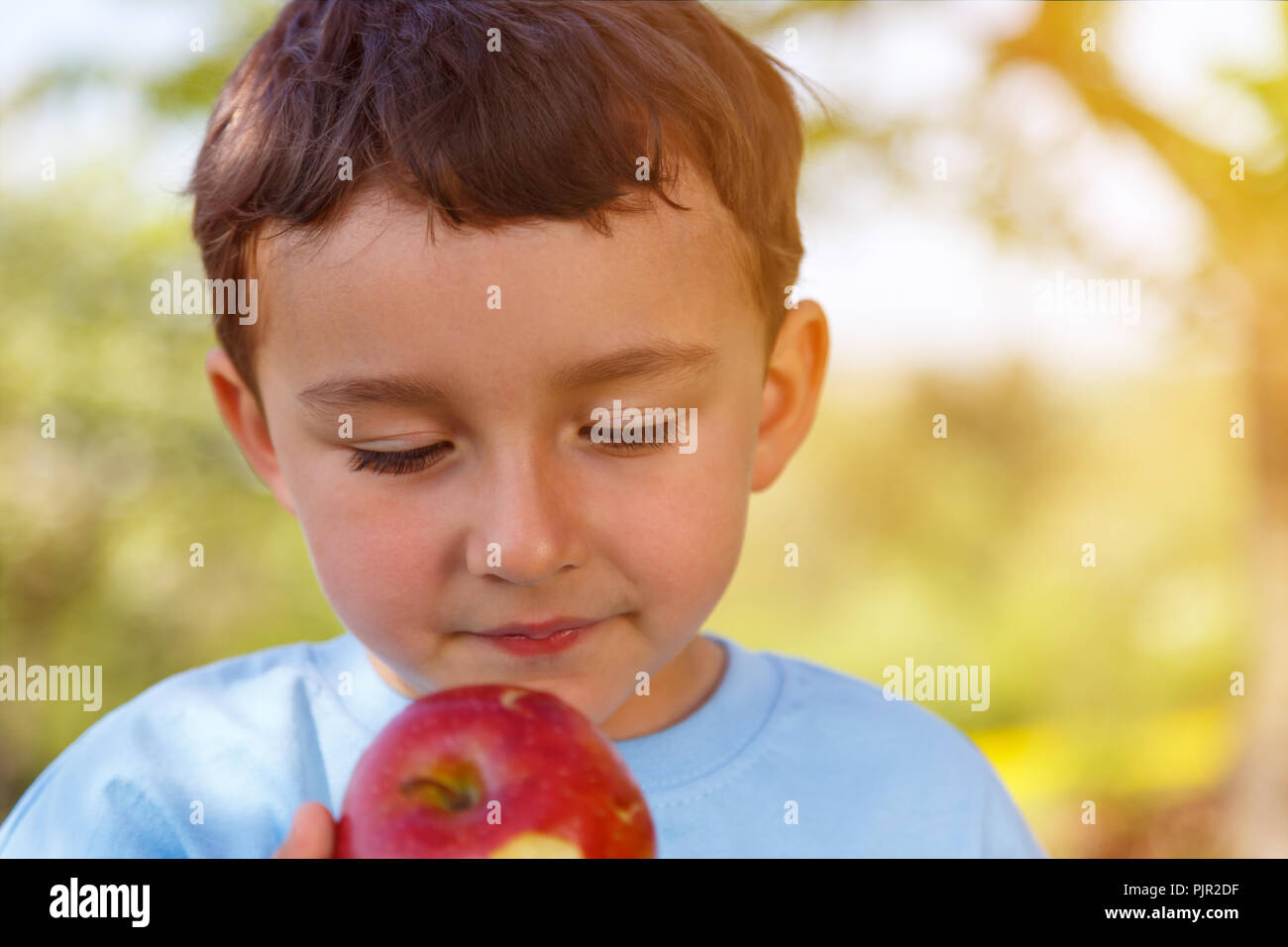 Bambino kid little boy mangiare frutta apple copyspace all'aperto all'aperto al di fuori di primavera la natura Foto Stock