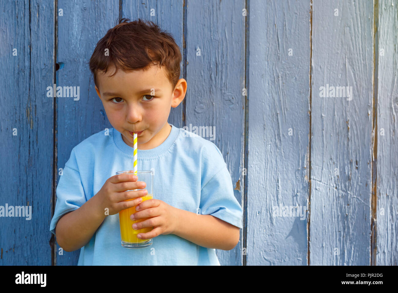 Bambino kid ragazzino di bere succo di arancia bere copyspace copia spazio all'aperto all'esterno del vetro esterno Foto Stock