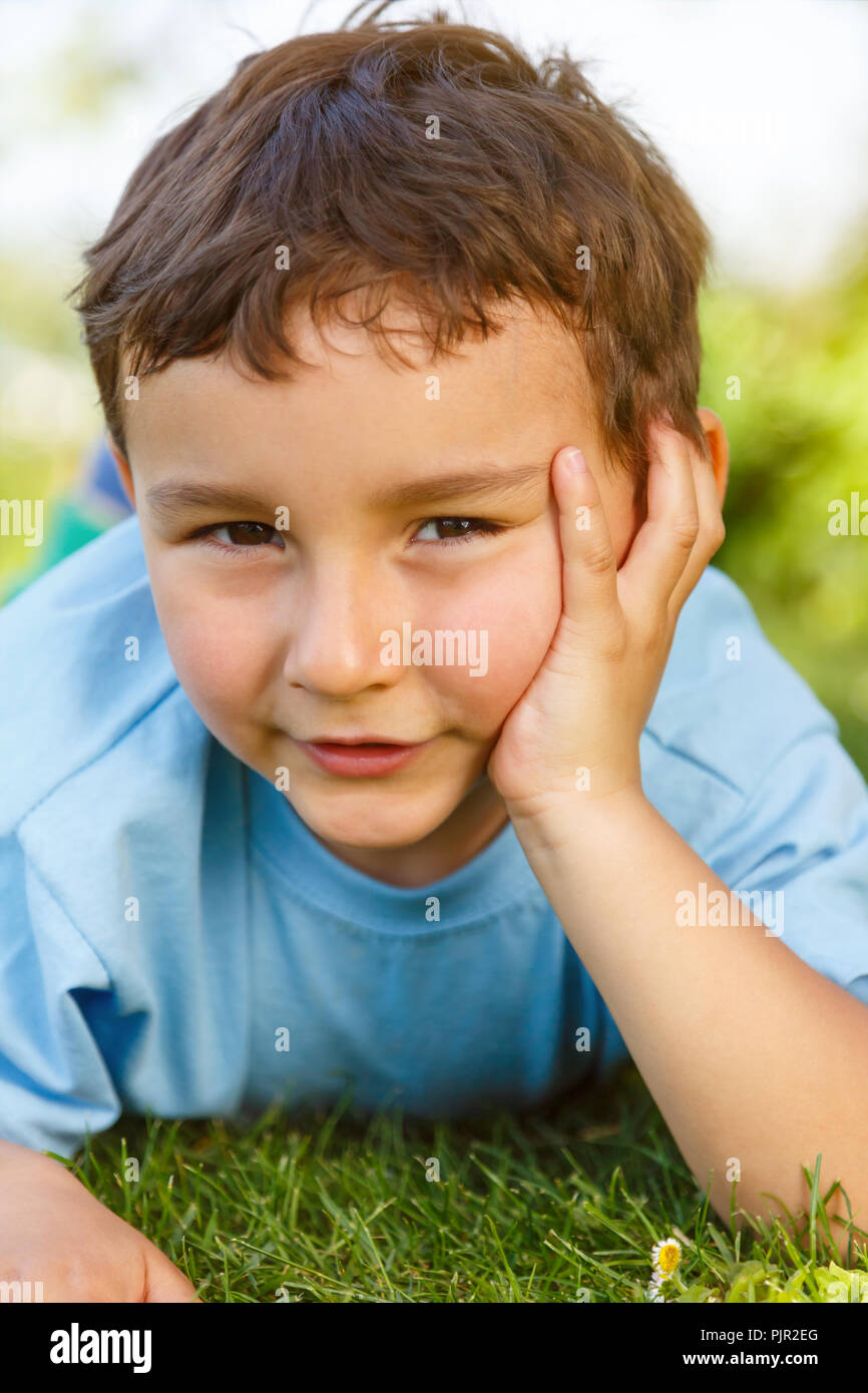 Bambino kid little boy pensare pensare guardando prato outdoor ritratto verticale formato Foto Stock