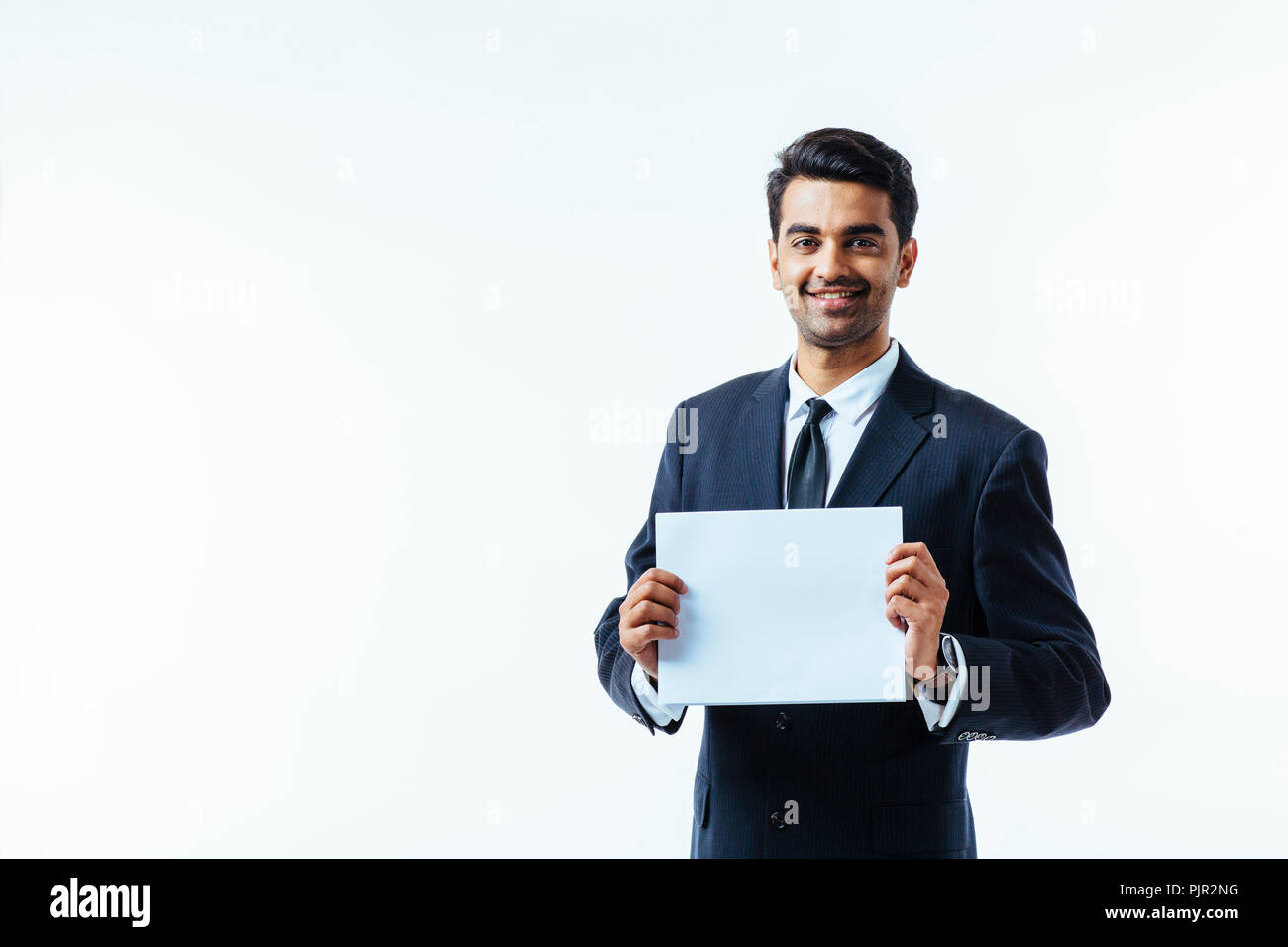 Ritratto di un uomo in business suit, guardando la telecamera, tenendo un cartoncino bianco con entrambe le mani, isolato su bianco di sfondo per studio Foto Stock