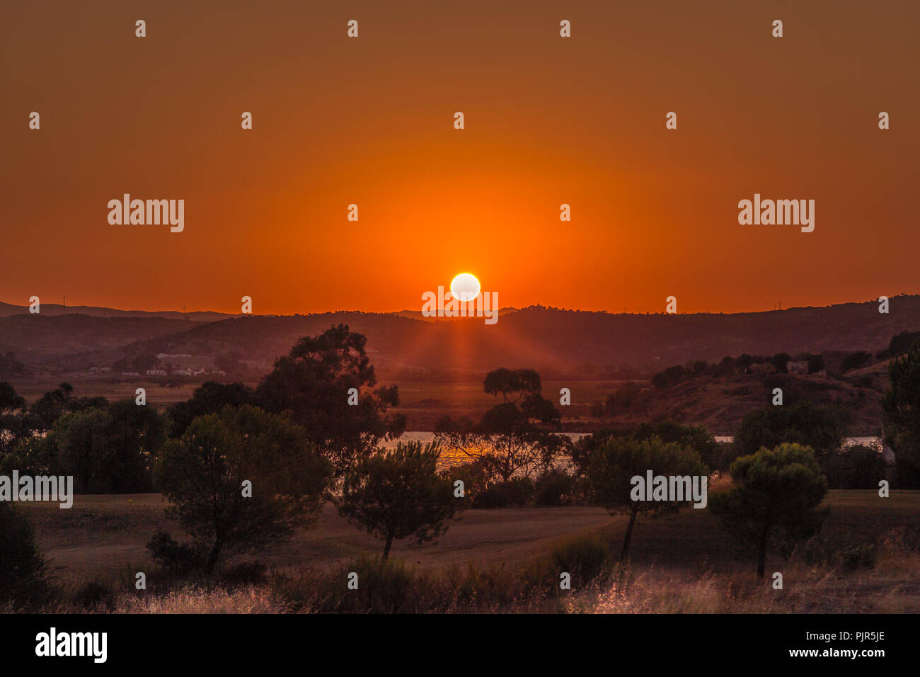 Tramonto Dorato con raggi nella foschia in Ayamonte Andalusia cercando di fronte al Portogallo. Foto Stock