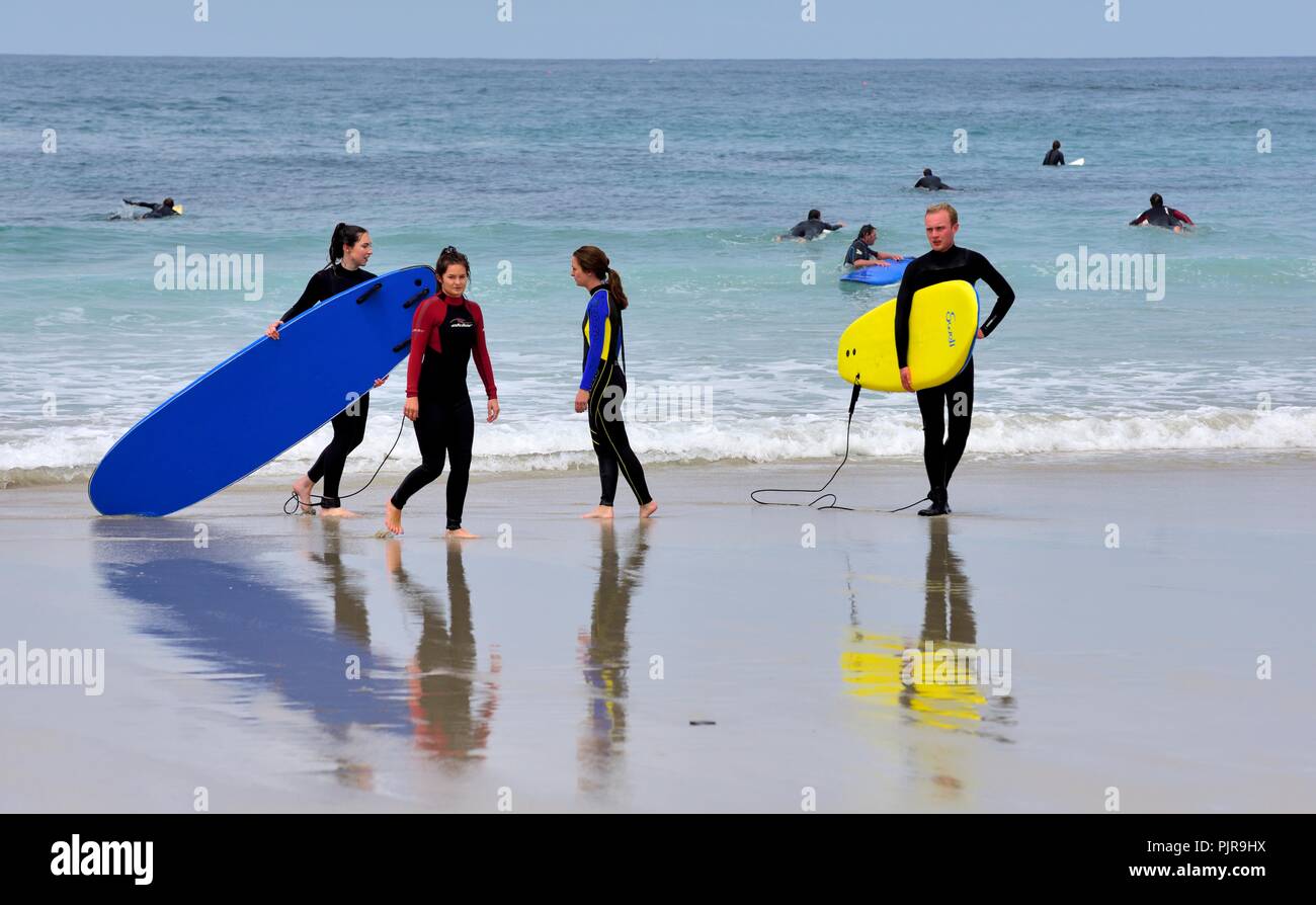I giovani che trasportano tavole da surf,Sennen Cove,Cornwall,l'Inghilterra,UK Foto Stock