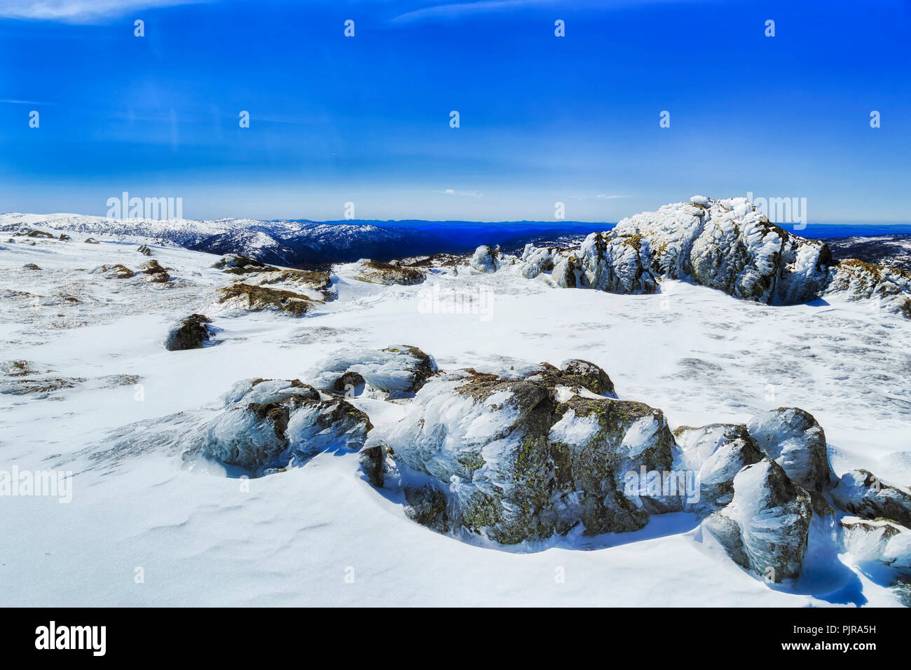 Coperta di neve cime del retro Perisher picco di montagna con rocce e moss su un freddo inverno pieno di sole al giorno durante la stagione sciistica. Foto Stock
