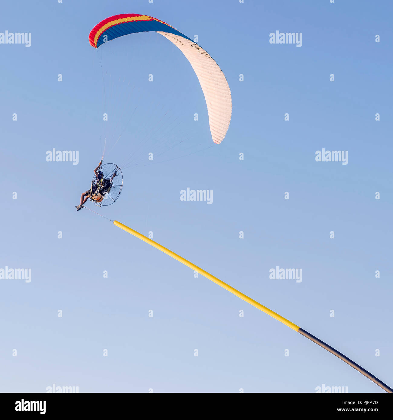 Paramotore rende pilota acrobazie con un banner attaccata al piede Foto Stock