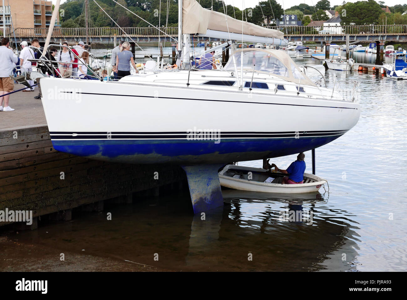Uomo a Lymington harbour riparare la parte inferiore di Yacht Foto Stock