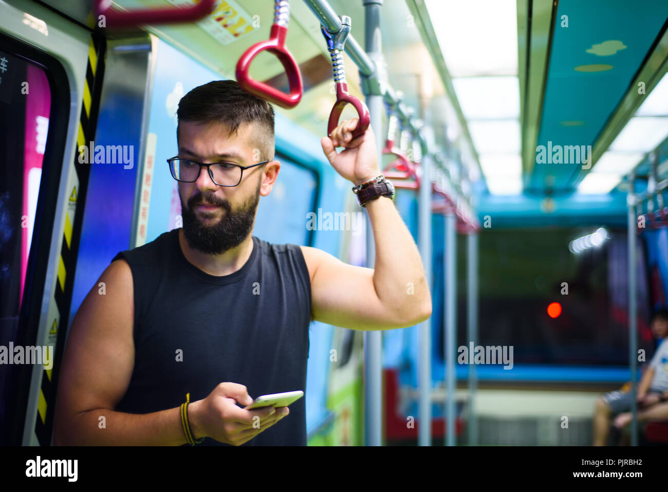 Uomo che utilizza smart phone mentre prendendo il treno della metropolitana Foto Stock