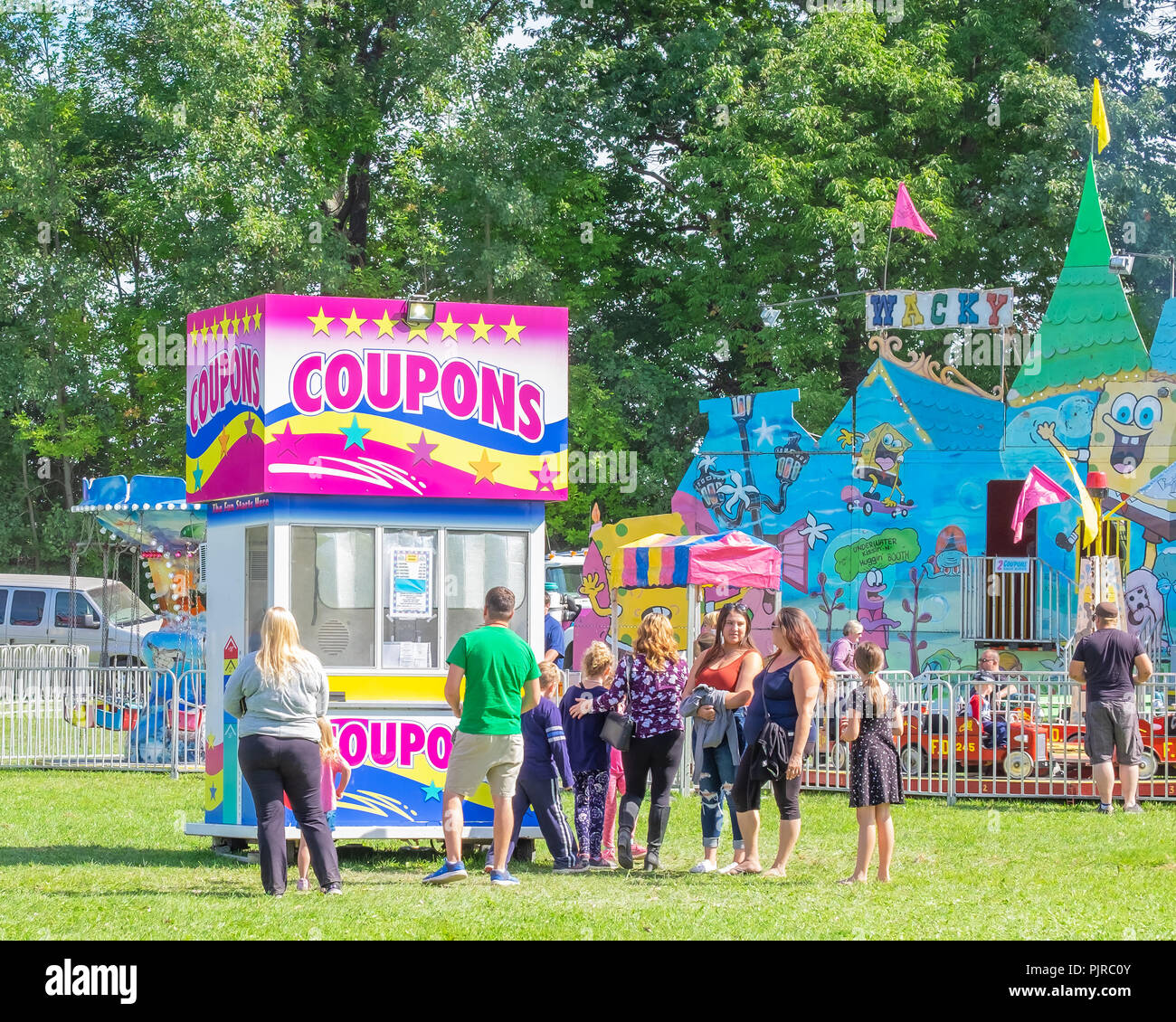 Linea di persone fino a un ticket booth in corrispondenza della zona dei divertimenti di un locale rientrano in fiera. Foto Stock