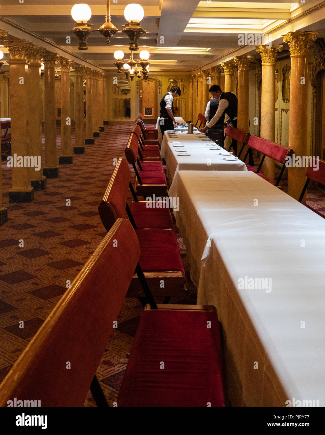 Il personale inizia a stendere il servizio della cena per un evento a bordo della SS Gran Bretagna nel oppulent salone da pranzo. Foto Stock