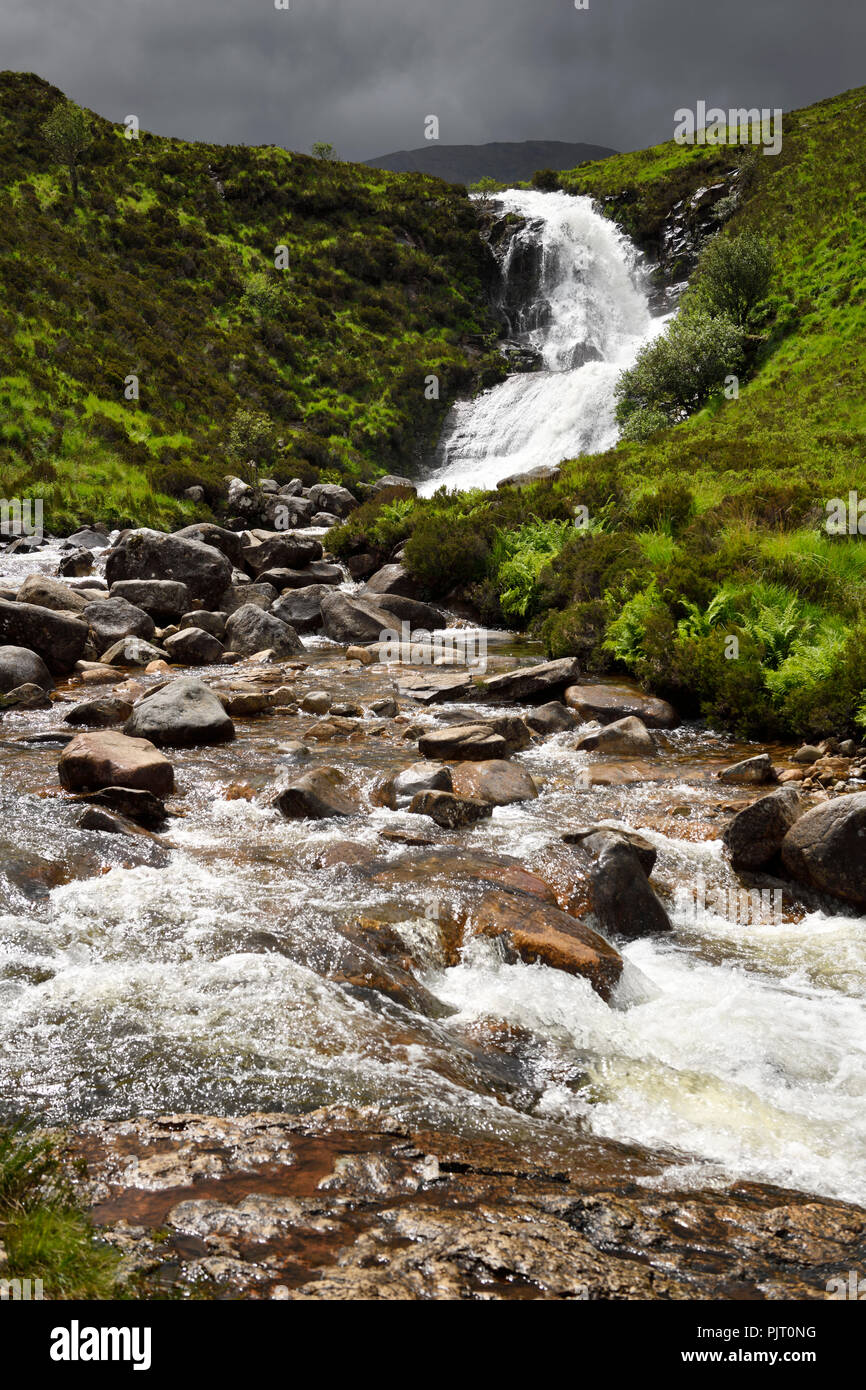 Sun su Blackhill Eas o un' Bhradain cascata sul Allt Coire nam Bruadaram fiume con nuvole scure Highlands scozzesi Isola di Skye in Scozia UK Foto Stock