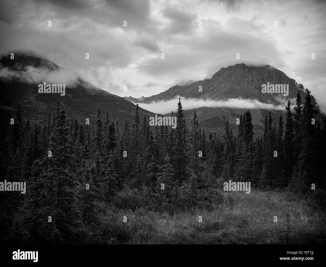 Nuvole appesa sopra la montagna in una foto in bianco e nero Foto Stock