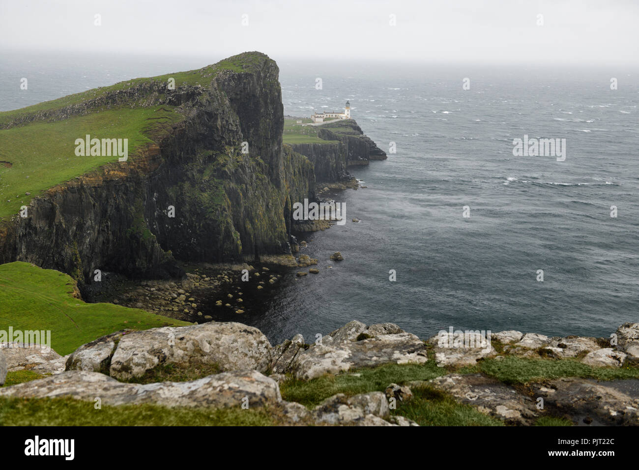 Neist Point Lighthouse in condizioni di vento forte e pioggia urticante con ripide scogliere di basalto per Oisgill Bay Oceano Atlantico Isola di Skye in Scozia UK Foto Stock