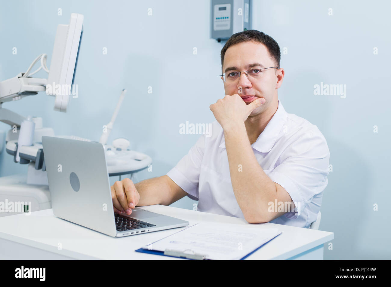 Ritratto di pensieroso smart oculista seduto alla clinica Foto Stock