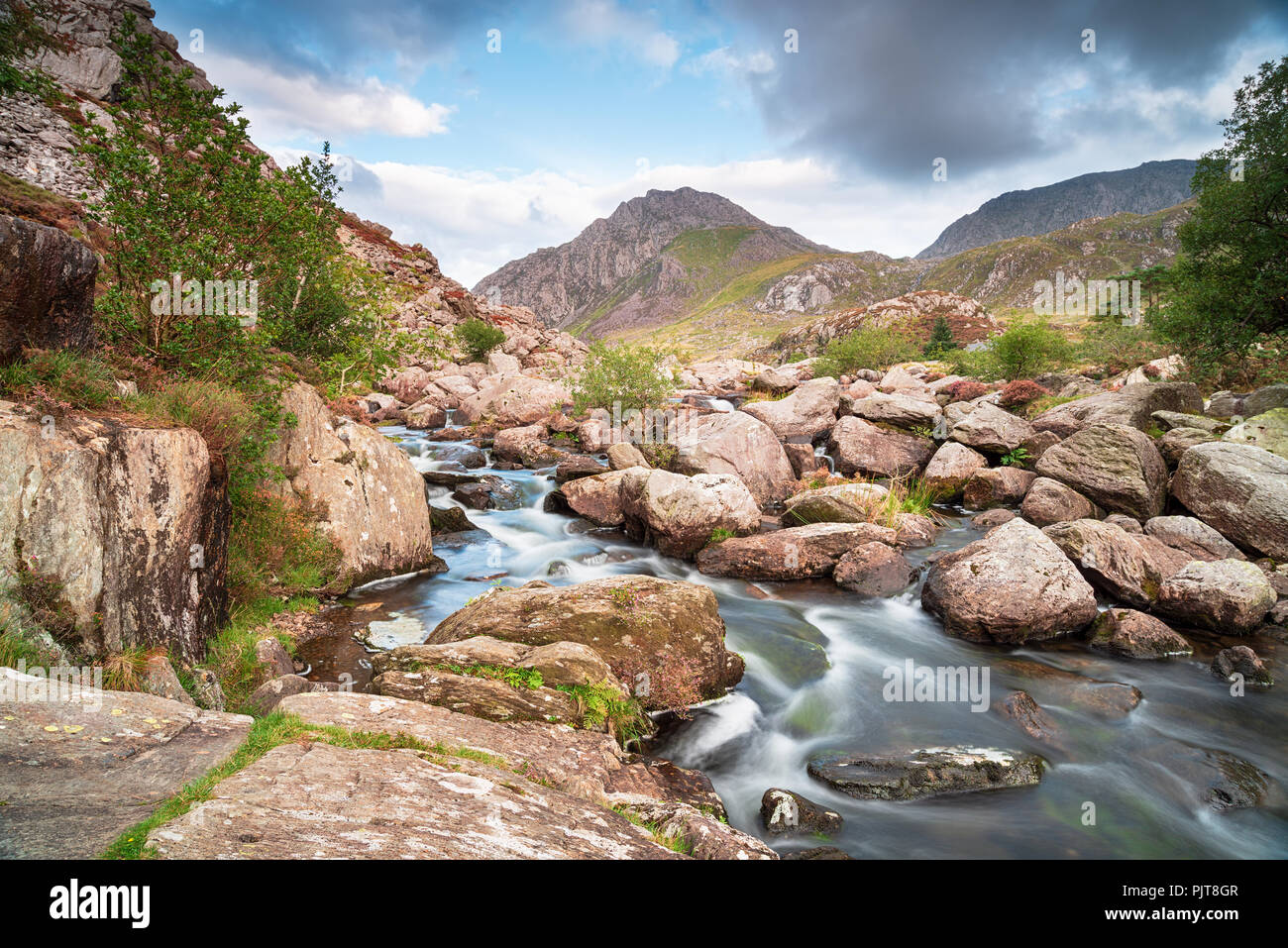 Il Afon Ogwen come cascades su rocce della valle Ogwen con il monte Tryfan in background Foto Stock