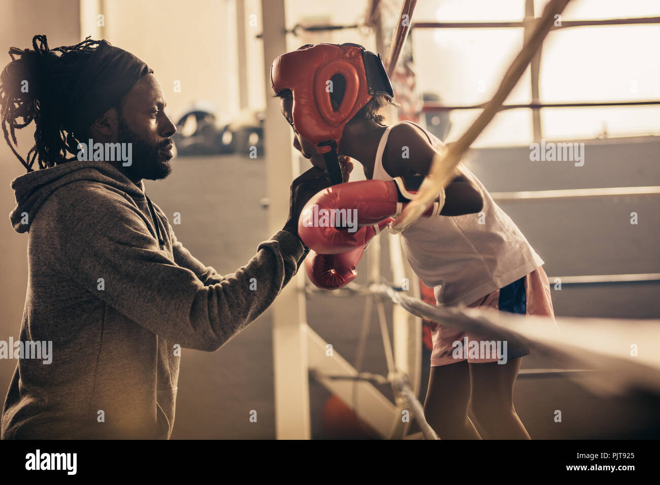 Boxing coach testa di legatura alla protezione di un pugile kid prima di una lotta. Kid boxer a parlare con il suo allenatore durante un incontro di pugilato. Foto Stock