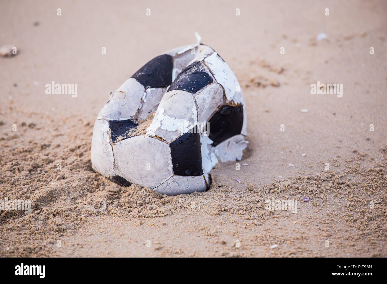 Il calcio vecchio, lacerato e segni di sporco sono stati lasciati sulla spiaggia. Foto Stock