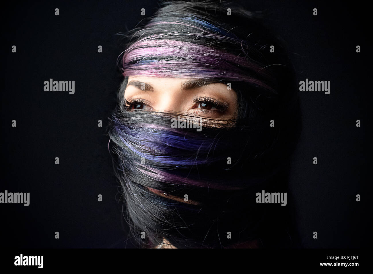 Ritratto di un volto di donna avvolta nel suo proprio capelli Foto Stock