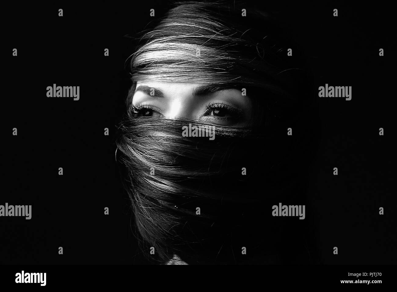 Ritratto di un volto di donna avvolta nel suo proprio capelli Foto Stock