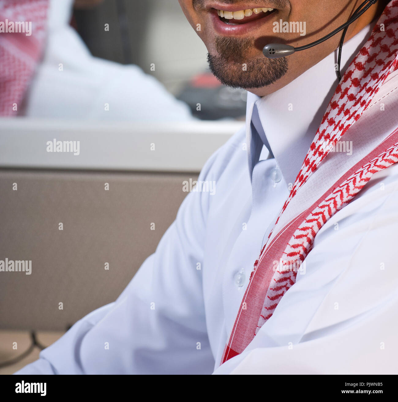 Ritratto di un sorridente medio orientale dipendente con cuffie su, in un call center Foto Stock