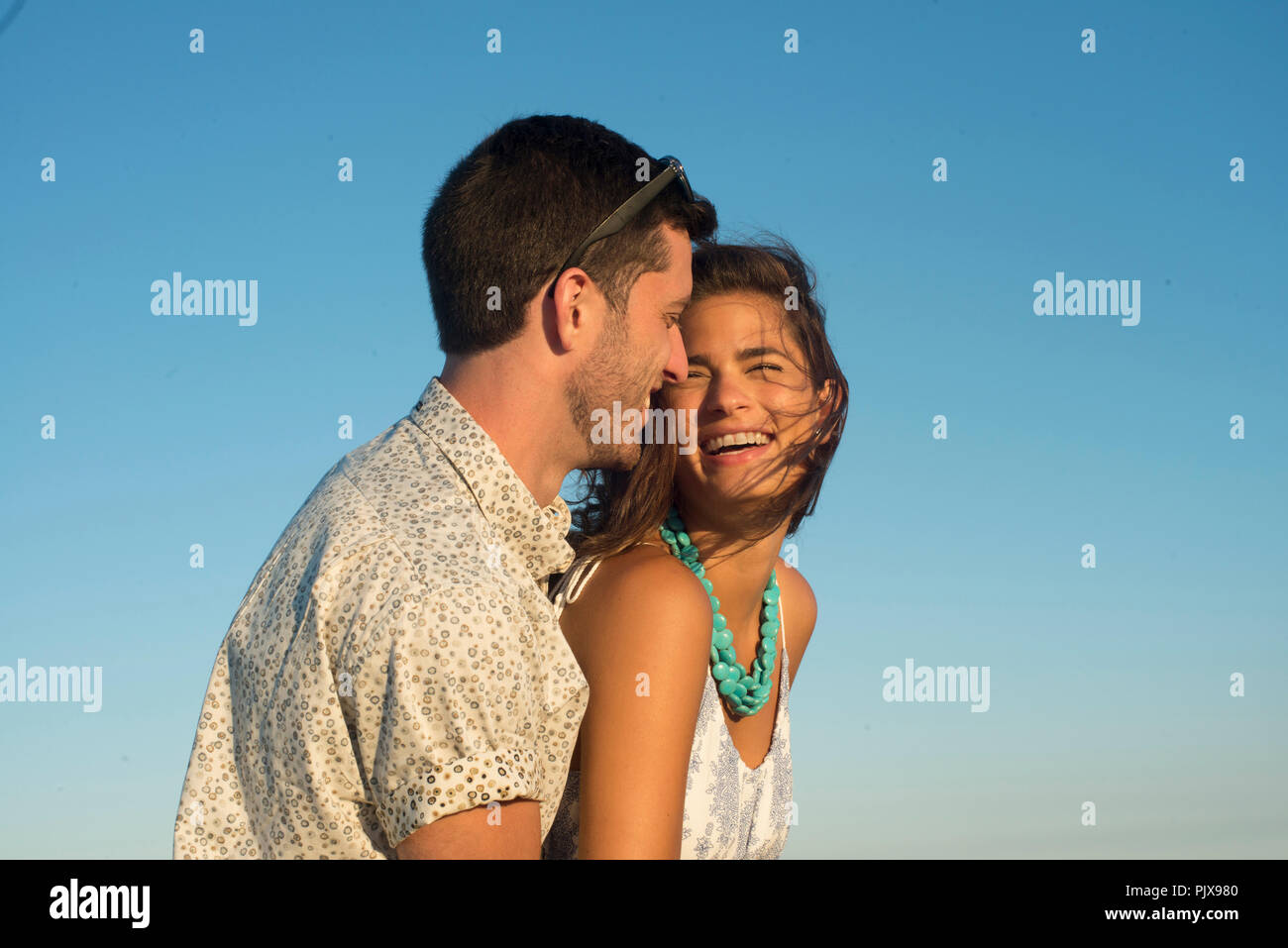 Romantico coppia giovane ridendo contro il cielo blu Foto Stock