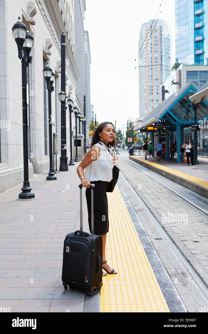 Imprenditrice in attesa sul light rail platform Foto Stock