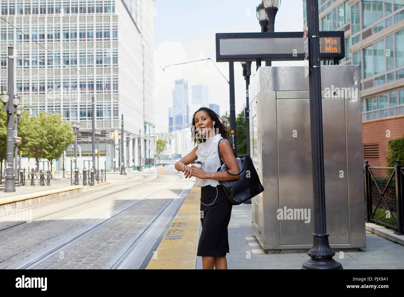 Imprenditrice in attesa sul light rail platform Foto Stock