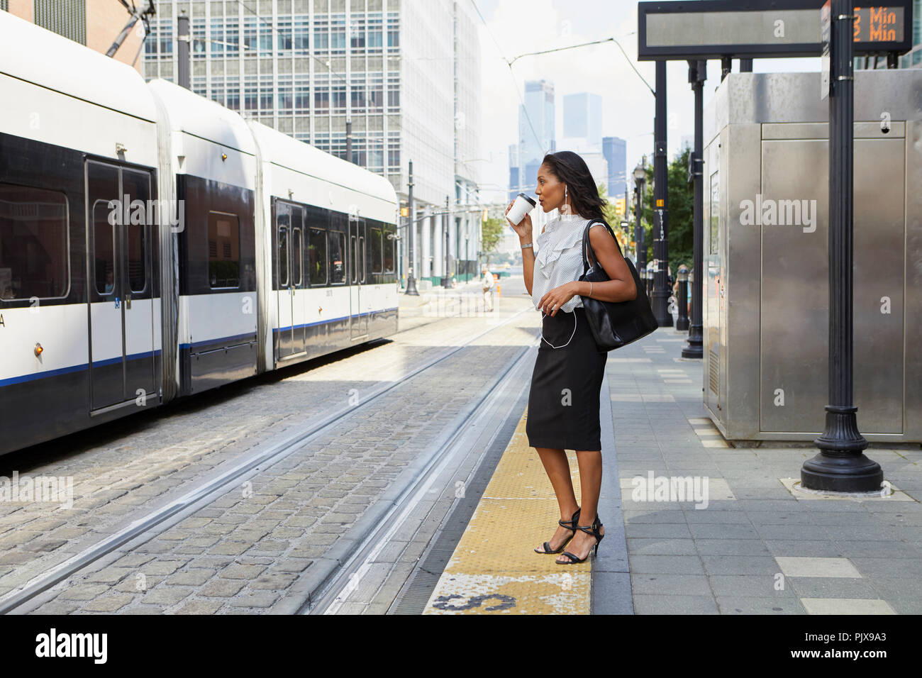 Imprenditrice in attesa sul light rail platform Foto Stock