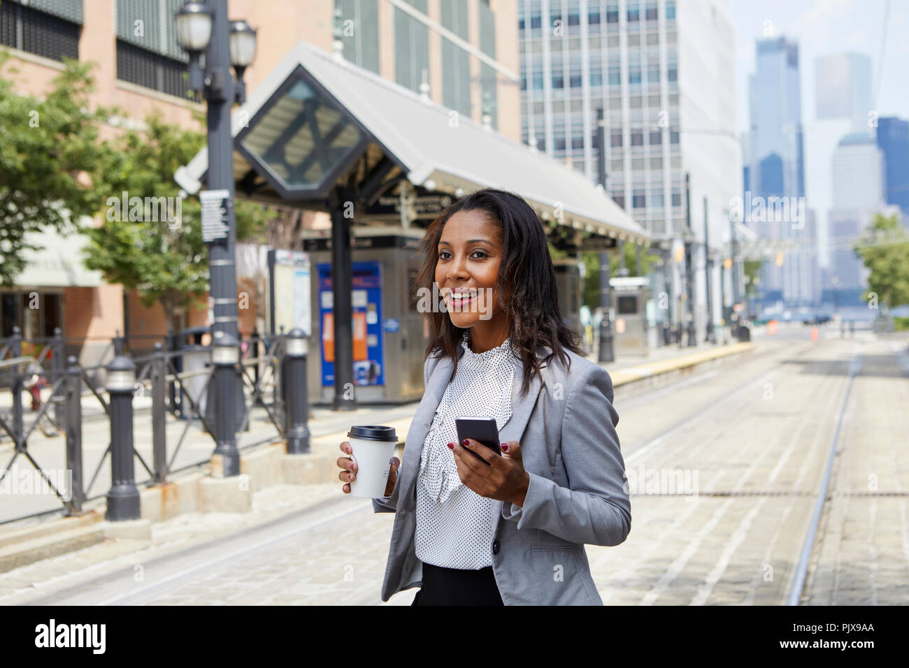 Imprenditrice tramite cellulare in light rail station Foto Stock