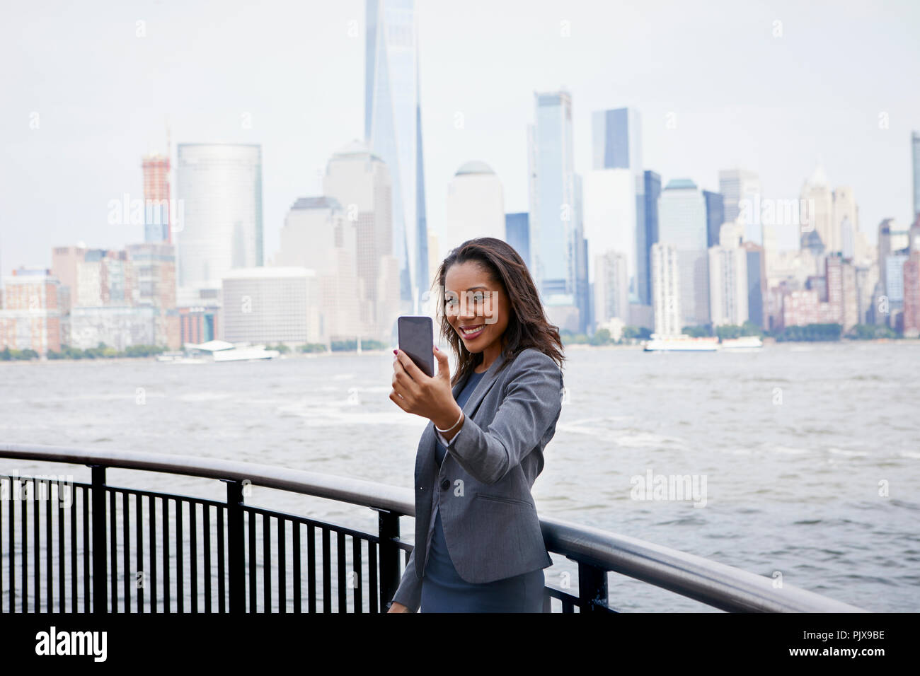 Imprenditrice tenendo selfie, New York skyline della città in background Foto Stock