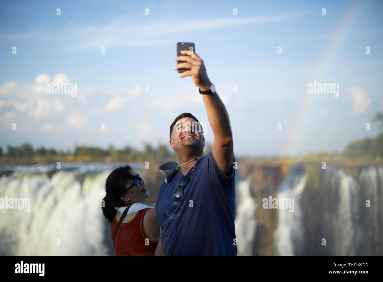 I turisti tenendo selfie, Victoria Falls, Zimbabwe Foto Stock