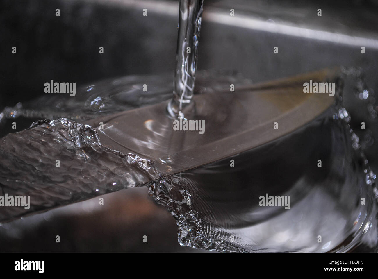 Il lavaggio di un coltello sotto un flusso di acqua Foto Stock