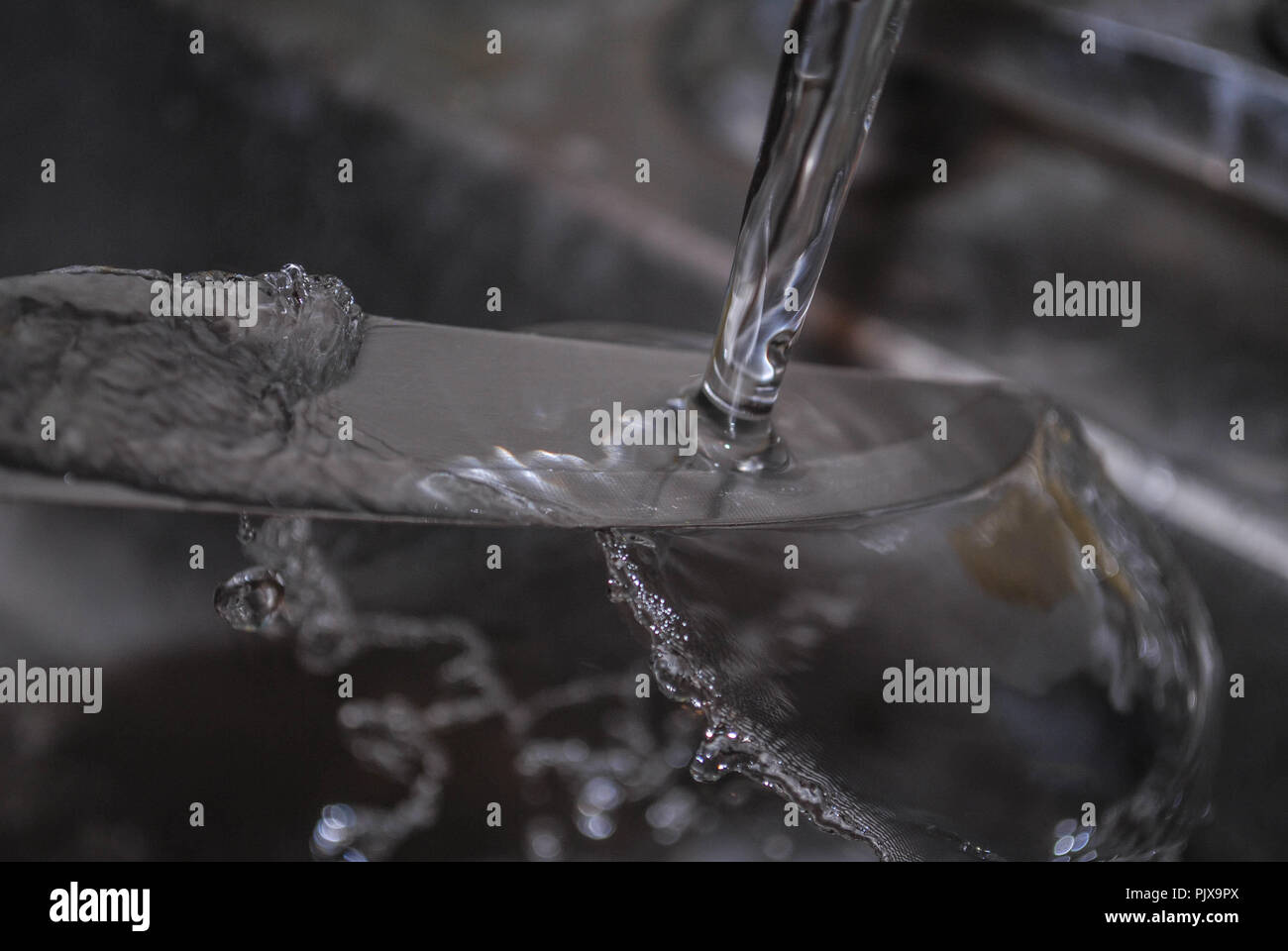 Il lavaggio di un coltello sotto un flusso di acqua Foto Stock