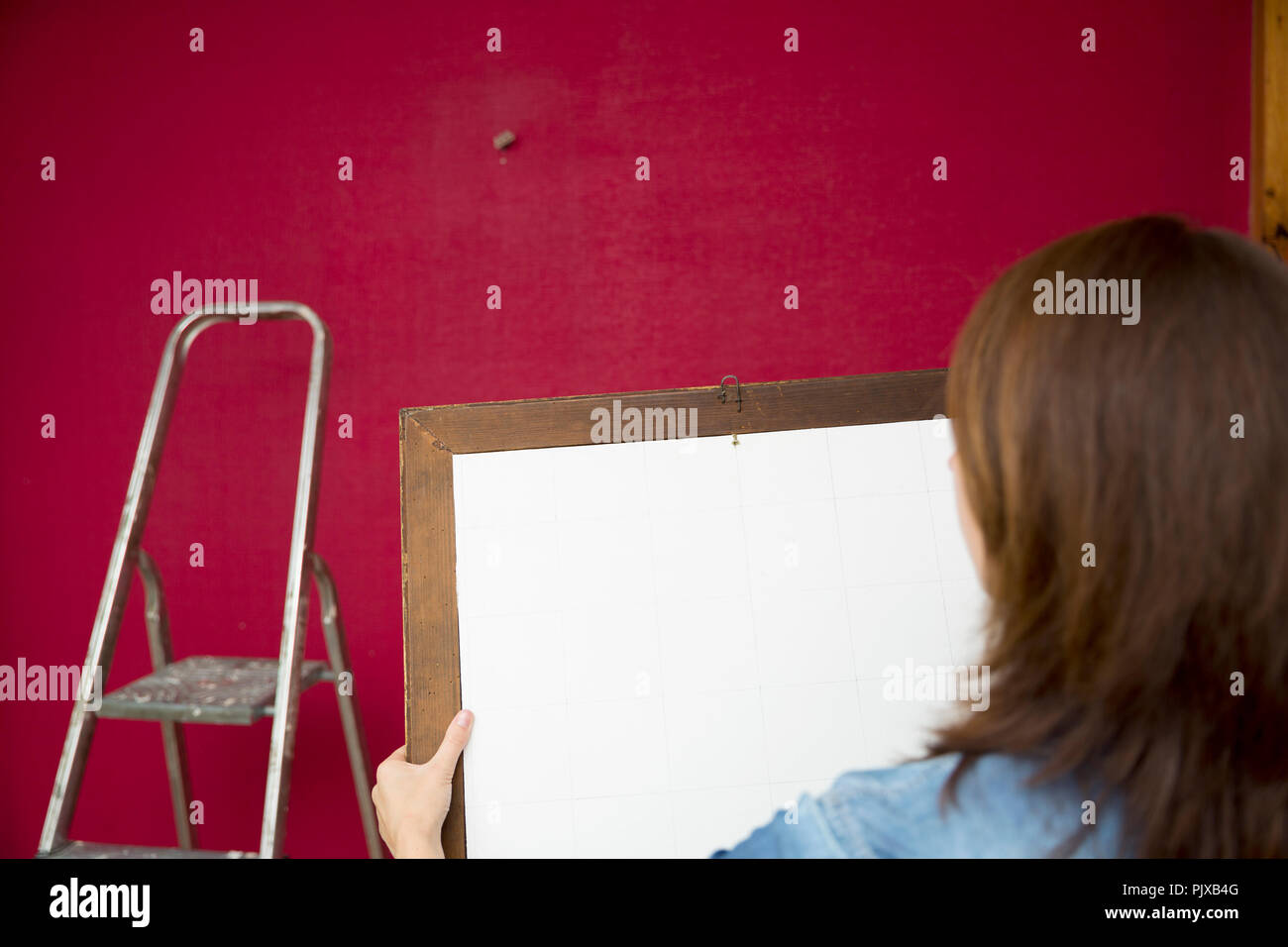 Miglioramento di casa. Belle Donne mettendo un dipinto su una parete in background leader in alluminio. Foto Stock