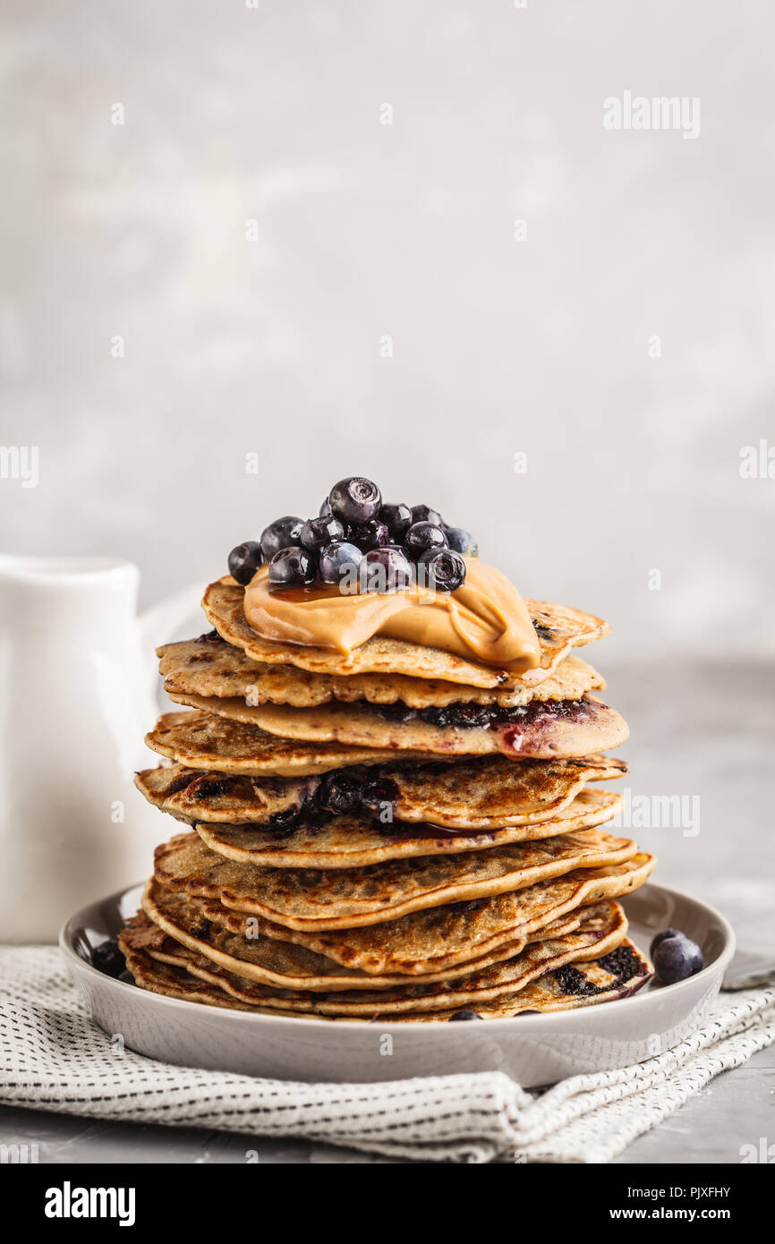 Pila vegane mirtillo frittelle con burro di arachidi e di sciroppo. Pulire il concetto di mangiare. Foto Stock