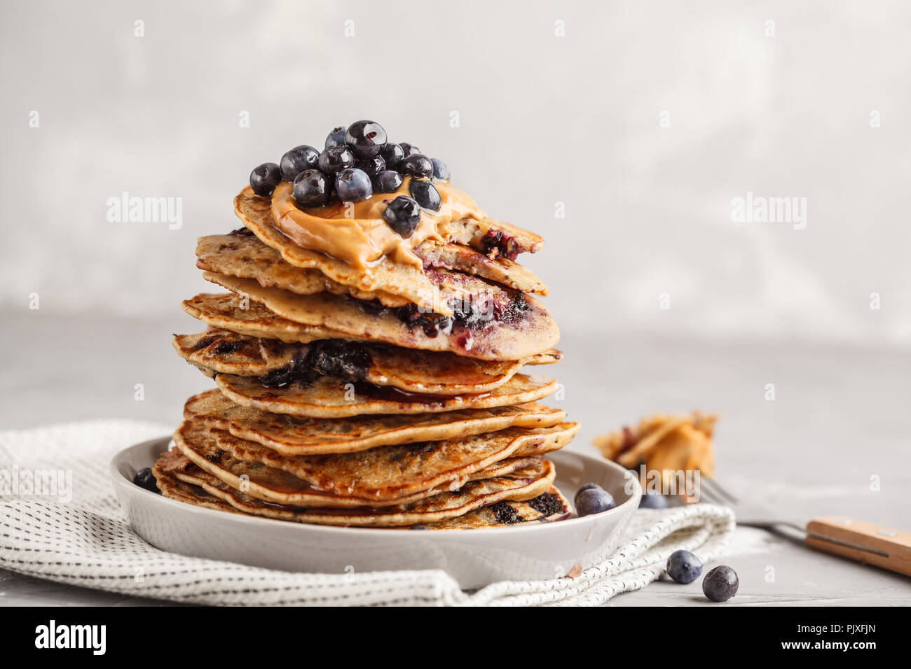 Pila vegane mirtillo frittelle con burro di arachidi e di sciroppo. Pulire il concetto di mangiare. Foto Stock